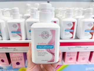 Woman holding bottle of pink hair color shampoo.