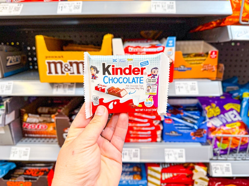 hand holding kinder chocolate bars in candy aisle at walmart