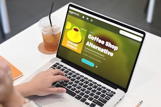 person with headphones listening to amazon music coffee shop alternative playlist on laptop