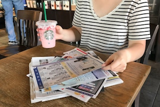 someone grabbing paper and starbucks drink in starbucks at a table