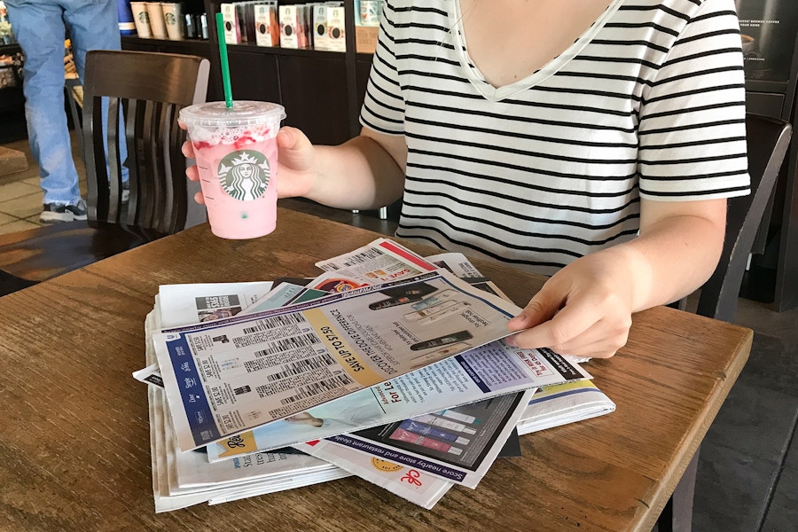 someone grabbing paper and starbucks drink in starbucks at a table