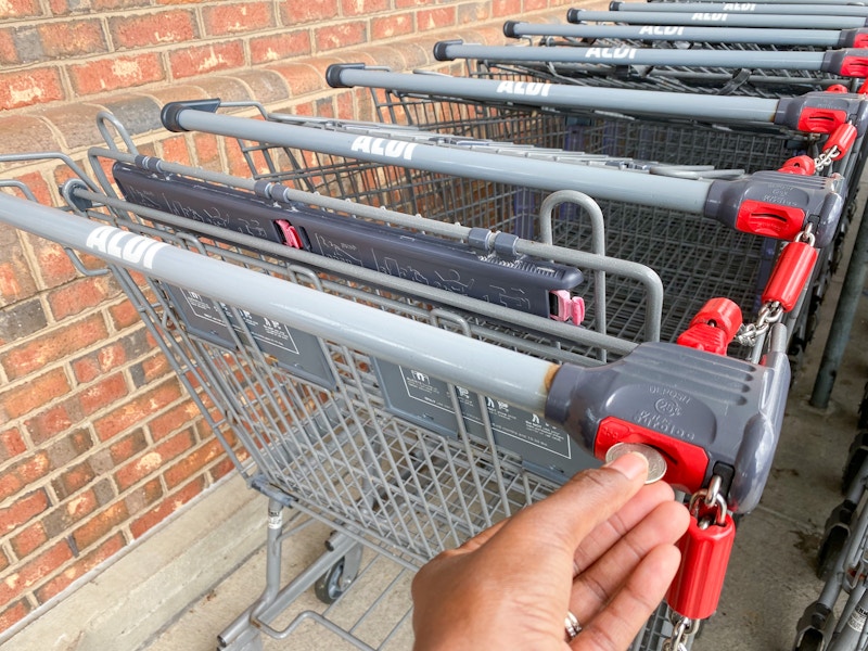 someone putting a quarter into an Aldi cart