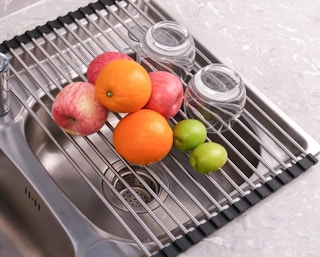 a drying rack with fruit and a glass on it