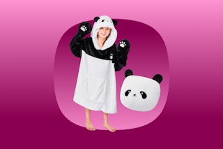 A child holds up their hands to show paw prints on the panda blanket hoodie. A hoodie folded into a panda head lies beside them.