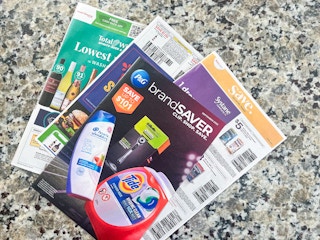 coupon inserts from the Sunday Newspaper in a pile on a counter top