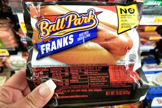 hand holding a pack of ball park franks