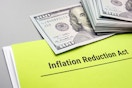 A document that reads, "Inflation Reduction Act" with a stack of hundred dollar bills.