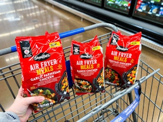 hand holding a stouffers air fryer meal over cart with two in walmart cart