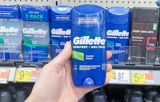 hand holding stick of gillette invisible solid deodorant in front of other sticks on walmart shelf