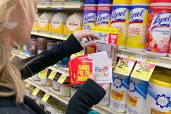Person holding coupons in front of Lysol disinfecting wipes