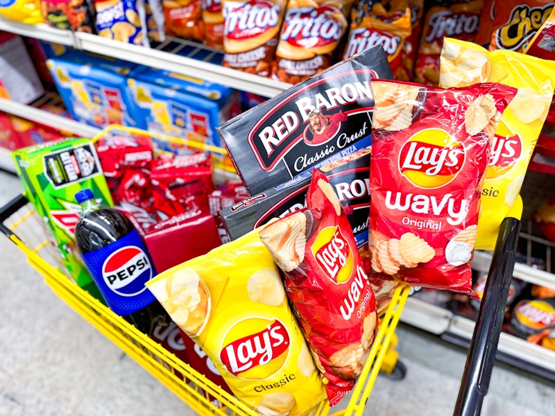 cart full of soda, chips, and pizza