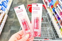 hand holding two neutrogena lip balms over a shopping cart
