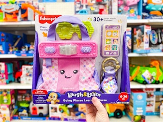 hand holding a fisher-price learning purse in front of a target cart