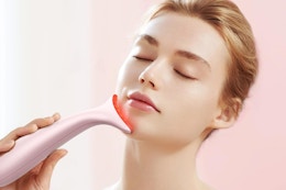 A woman massages her face and treats it with red light using this nifty tool