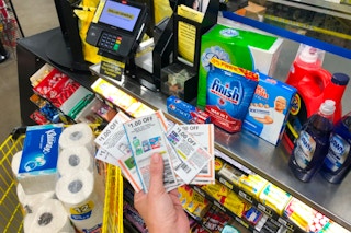 Hand holding Dollar General coupons with Dollar General products