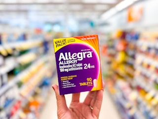 hand holding box of Allegra allergy medicine at Walgreens in the store aisle