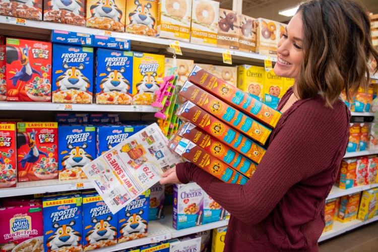 Person holds stack of cereal boxes in cereal aisle smiling widely