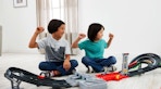 two kids playing with a F1 track set