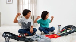 two kids playing with a F1 track set