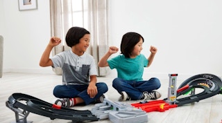 two kids playing with a F1 track set
