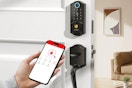 a person holding a phone next to a smart door lock