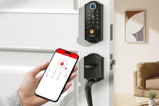 a person holding a phone next to a smart door lock