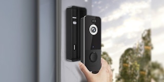 hand putting a wireless doorbell security camera onto a door frame