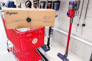 A Dyson vacuum in a Target shopping cart parked next to a display.