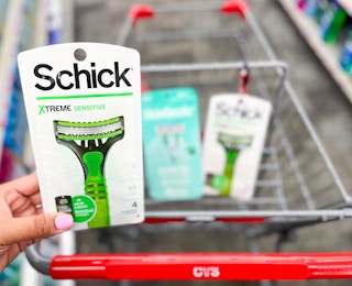 hand holding Schick razor pack in front of shopping cart with pack of Skintimate and Schick razors inside