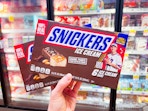 hand holding boxes of snickers ice cream bars