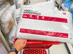 hand pushing cart filled with room-essentials-bed-pillows in target aisle