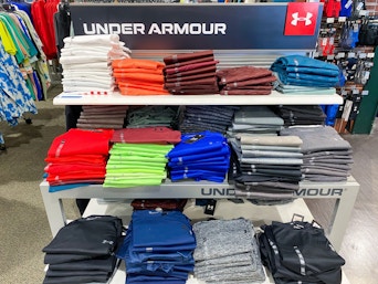 A variety of Under Armour shirts folded on a shelf in Dicks Sporting Goods