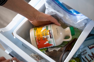 A person pulling a container of pure maple syrup from the freezer