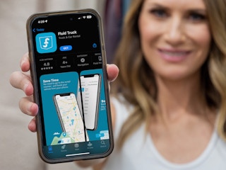 A person holding up a phone displaying the App Store page for the app FluidTruck