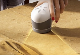 a hand using a fabric shaver on a piece of fabric