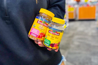 person holding 2 bottles of nature made vitamins