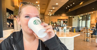 A person drinking coffee from a Starbucks cup in a Starbucks