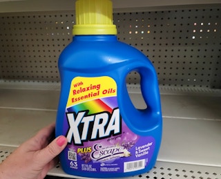 hand touching xtra detergent on store shelf