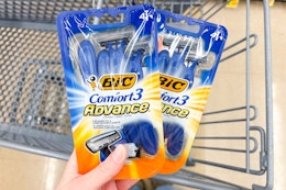hand holding packs of bic razors over shopping cart