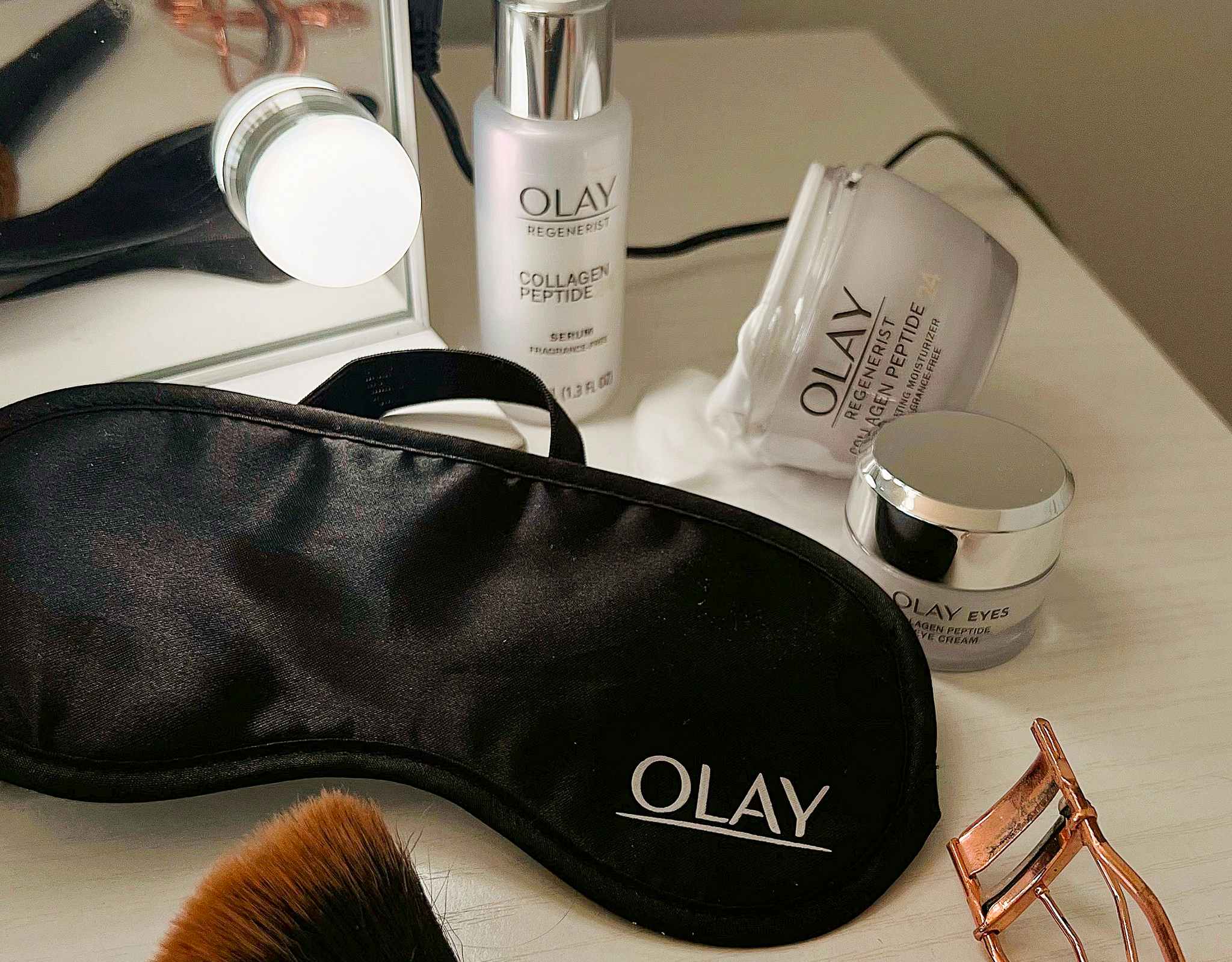 An Olay sleep mask on a vanity table with Olay products and other beauty tools.