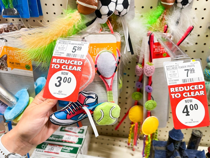 A person's hand taking a cat toy off of a wall of the reduced to clear clearance section at PetSmart