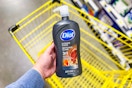 hand holding a bottle of dial men body wash above yellow shopping cart