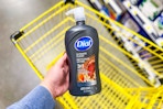 hand holding a bottle of dial men body wash above yellow shopping cart
