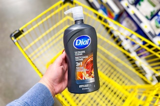 hand holding a bottle of dial men body wash above yellow shopping cart