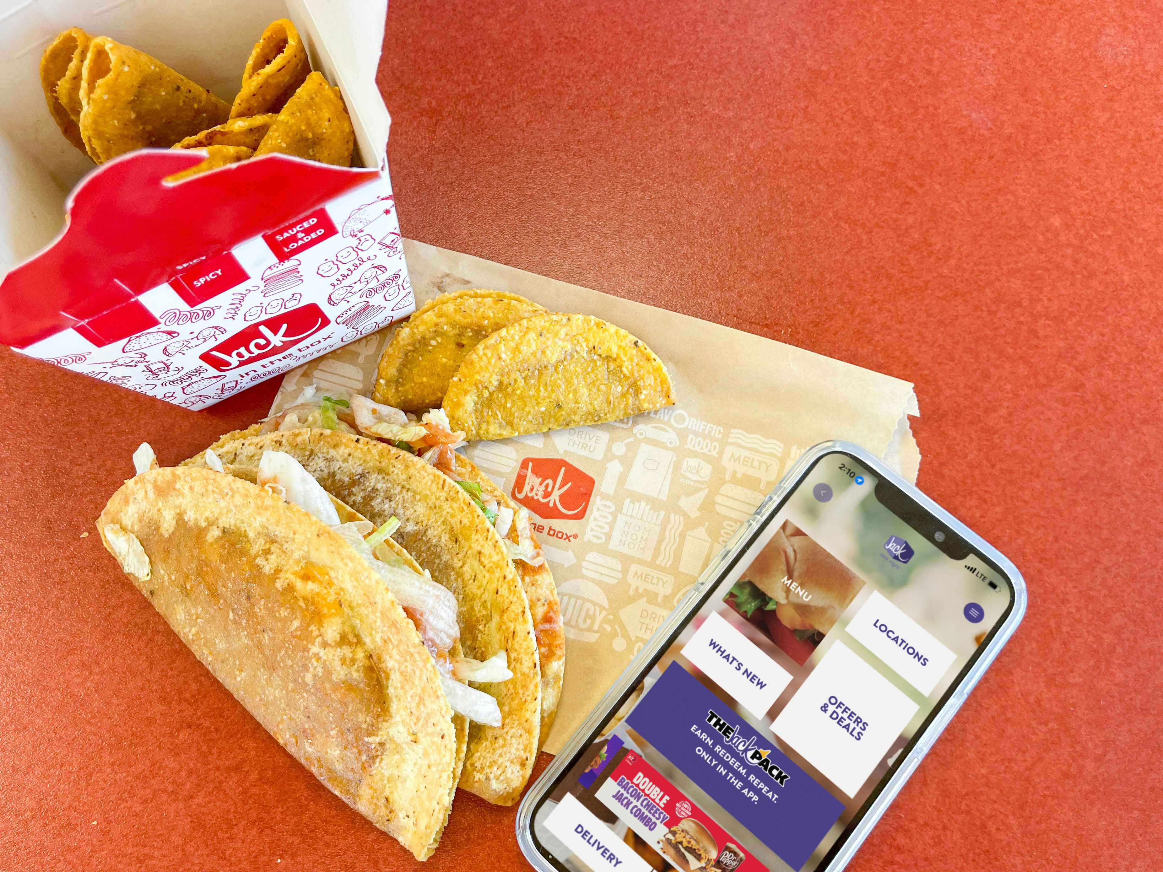 box of tacos on table with a cellphone on table with jack in the box app on screen