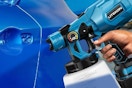 a cordless paint sprayer spraying on a car