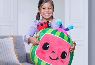 A little girl holding a Cocomelon Cuddle Pillow Melon