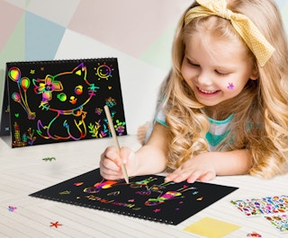 A girl drawing on rainbow scratch paper