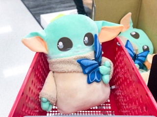 A Baby Yoda Giant Cuddle Plush in a Target shopping cart.