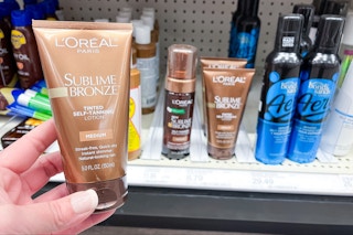 hand holding a tube of L'Oreal Paris self-tanning lotion at target